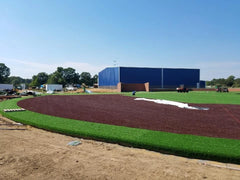 Steel building kit with blue rigid frame and dark red turf sections under construction on a sunny day. — supplier listing reference; configuration may vary.
