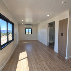 Modular homes workforce housing trailer with light wood floor, black windows, and two wooden closets in desert setting. — supplier listing reference; configuration may vary.